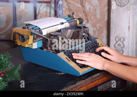 Hands type text on old typewriter on desk with leather top in studio Stock Photo