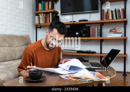 Young man freelance architect or interior designer working alone from small cozy home office. Educated and creative independent male using laptop comp Stock Photo