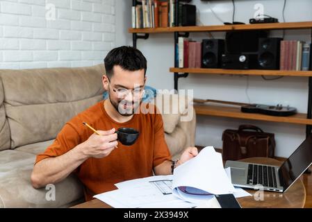 Young man freelance architect or interior designer working alone from small cozy home office. Educated and creative independent male using laptop comp Stock Photo