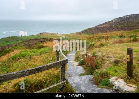 Narrow fenced path with steps leading to a clifftop viewpoint on a lighthouse along the coast of Northern Wales on a foggy summer day Stock Photo