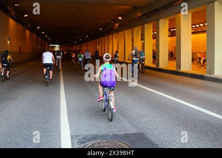 Many people ride bicycle in tunnel during bike parade in city, back view Stock Photo