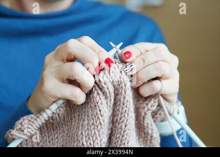 Hands of knitting woman in blue dress, close up view, noface Stock Photo