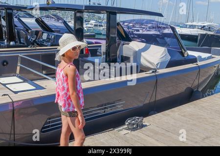 girl in hat and sunglasses walking on pier among luxury yachts Stock Photo