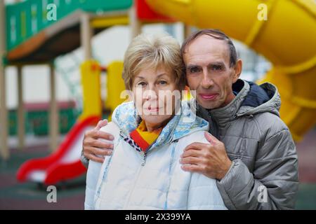 Elderly woman and man embrace on playground at autumn, shallow dof Stock Photo