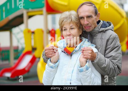 Elderly woman and man stand together on playground at autumn, shallow dof Stock Photo