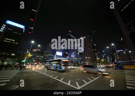 SEOUL - NOV, 3, 2015: People crossing road on crosswalk and cars move at night. Pedestrians in Seoul can now more safely get to streets of central are Stock Photo