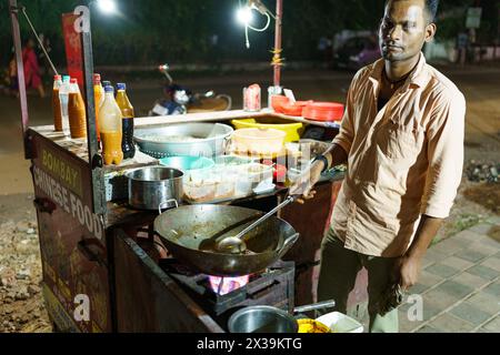 Mumbai, India - 20 October 2023: young street food vendor at a food stall on the street. Street food seller at night Stock Photo