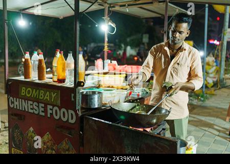 Mumbai, India - 20 October 2023: young street food vendor at a food stall on the street. Street food seller at night Stock Photo