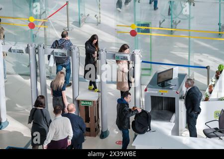 Moscow - April 10, 2024: Conference visitors including men and women of various ages go through security checks in a contemporary hall setting, highlighting routine safety procedures. Stock Photo