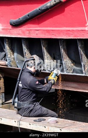 Around Bristol Harbourside. The Marianne of Manchester in dry dock at the Underfall Yard. Engineer using an angle grinder Stock Photo