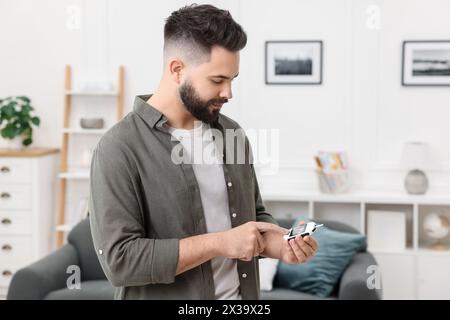 Diabetes test. Man using glucometer at home Stock Photo