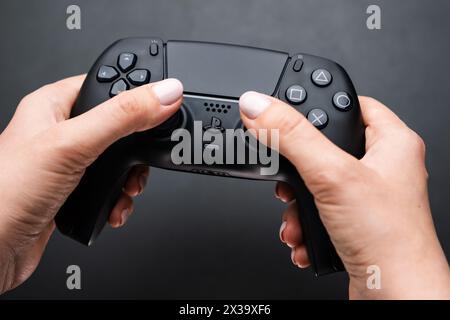 BERLIN , GERMANY - FEBRUARY 14 2024: Video game controller in womans hand on the black ground. Stock Photo