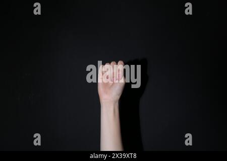 SOS gesture. Woman showing signal for help behind her back on black ...