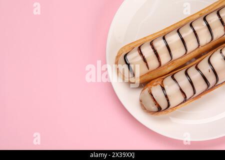 Delicious eclairs covered with glaze on pink background, top view. Space for text Stock Photo