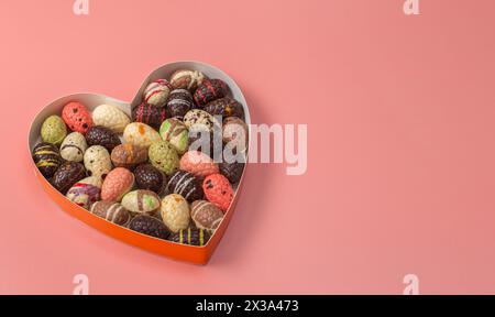 Assorted gourmet of Chocolate Easter eggs in a heart-shaped box on a rose background. Stock Photo