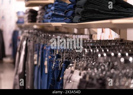 Colorful jeans in the store. Background theme of the trade sale. Clothes on a hanger in the store Stock Photo