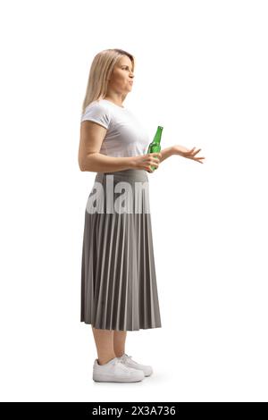 Full length profile shot of a young woman holding a bottle of beer isolated on white background Stock Photo