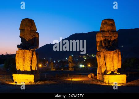 The Colossi of Memnon (colossal statues of Pharaoh Amenhotep III) at twilight on the West Bank of Luxor, Egypt Stock Photo