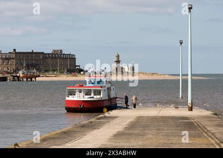 The ferry waits to depart from the slipway at Knott End-on-Sea, across the estuary to Fleetwood, Lancashire. The scene was painted by L. S. Lowry. Stock Photo