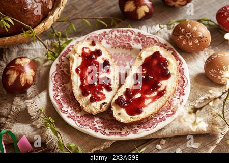 Two slices of traditional Czech sweet Easter cake called mazanec with butter and cranberry marmalade with dyed eggs Stock Photo