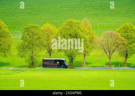 UPS Lieferwagen auf einer Landstraße, grüne Felder, Wiesen, Bäume säumen die 2-spurige Straße, Frühjahr, bei Schwelm, NRW, Deutschland, Landstraße *** UPS delivery van on a country road, green fields, meadows, trees line the 2-lane road, spring, near Schwelm, NRW, Germany, country road Stock Photo