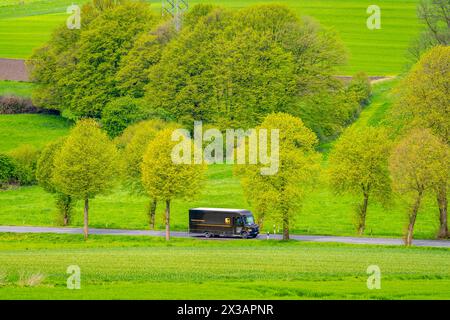 UPS Lieferwagen auf einer Landstraße, grüne Felder, Wiesen, Bäume säumen die 2-spurige Straße, Frühjahr, bei Schwelm, NRW, Deutschland, Landstraße *** UPS delivery van on a country road, green fields, meadows, trees line the 2-lane road, spring, near Schwelm, NRW, Germany, country road Stock Photo