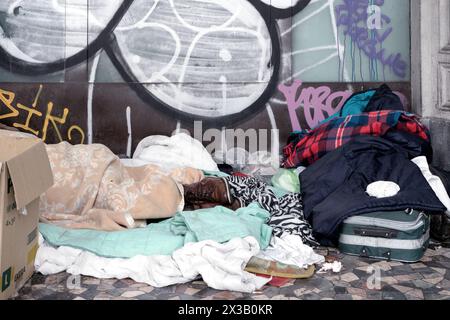 Italy, Rome: a homeless man sleeps lying with his shoes on his feet between the blankets Stock Photo