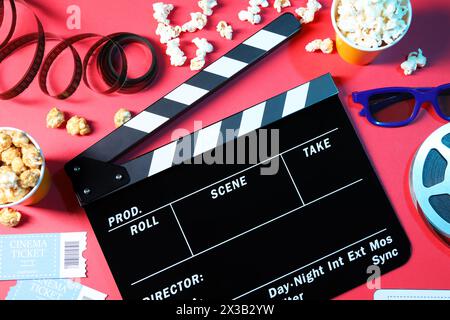 Flat lay composition with clapperboard and popcorn on red background Stock Photo