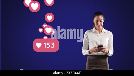 Image of Caucasian woman using smartphone over heart emojis floating on blue background Stock Photo