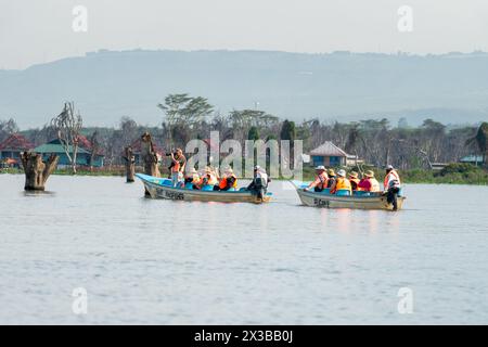 Tourists in a boat look on the antelopes waterbuck. Safari, Naivasha Lake, Kenya. February 2, 2024. Stock Photo