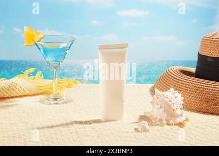 On a scarf, an empty label tube decorated with conch shells, a summer hat and a cocktail glass. Background of the beach and blue sky. Facial skin cosm Stock Photo