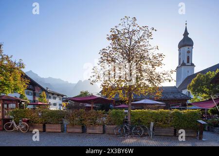 Restaurant and beer garden Fischers Mohrenplatz with parish church St. Martin and Wetterstein mountains in autumn in the evening light, district Stock Photo