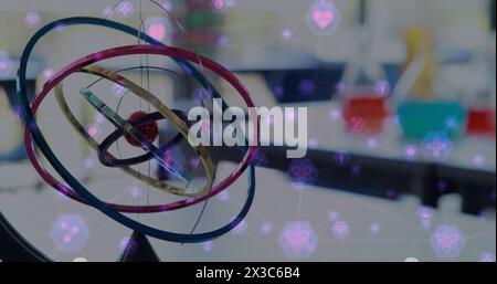 Image of network of connection with interface icons over model of atom moving in laboratory Stock Photo