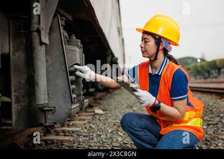 Train locomotive engineer women worker. Young teen Asian working check service maintenance train using tablet computer software. Stock Photo