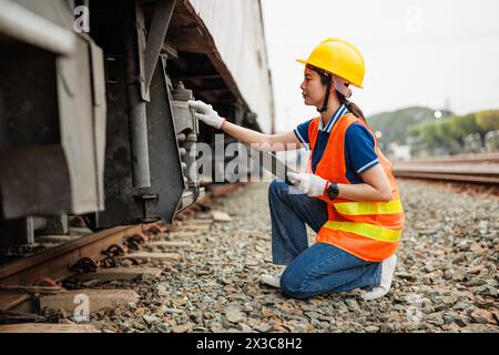 Train locomotive engineer women worker. Young teen Asian working check service maintenance train using tablet computer software. Stock Photo