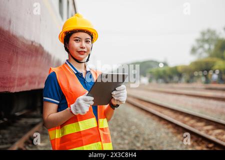 Train locomotive engineer women worker. Young teen Asian working check service maintenance train using tablet computer software. Stock Photo
