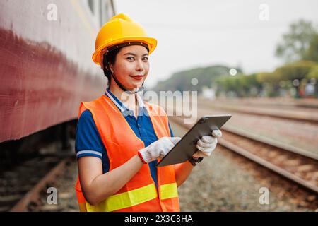 Train locomotive engineer women worker. Young teen Asian working check service maintenance train using tablet computer software. Stock Photo