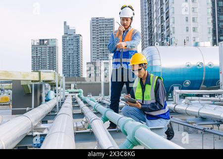 engineer teamwork technician workers service hotel boiler tank hot water supply pipe system. team working safety checking maintenance pipeline heating Stock Photo