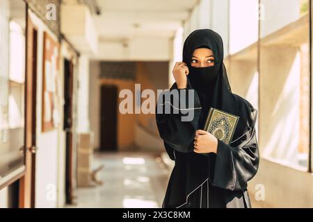 Muslim niqab woman read and learning the Quran and faith The Holy Al Quran book. Arab saudi black chador lady.arabic calligraphy translate meaning of Stock Photo