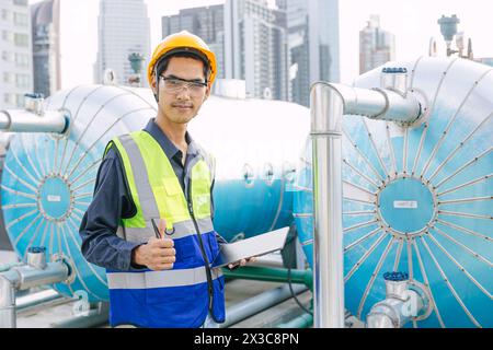 portrait gas pipe engineer worker on site service working maintenance hot water tank at roof top outdoor commercial building happy smiling. Stock Photo