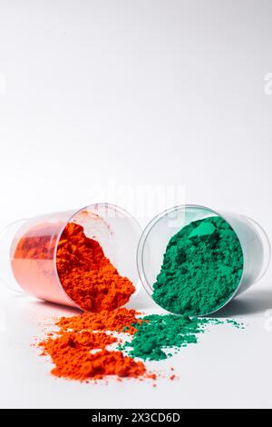 Colorful holi powder in a glass container leaning against a white background. selective focus Stock Photo