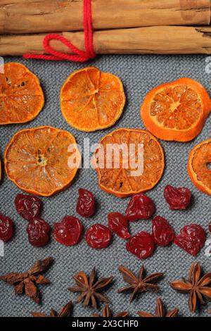 Dried tangerines, cut into pieces to decorate the dessert. Nearby are dry cherries, anise and cinnamon sticks tied with red thread. On a gray backgrou Stock Photo