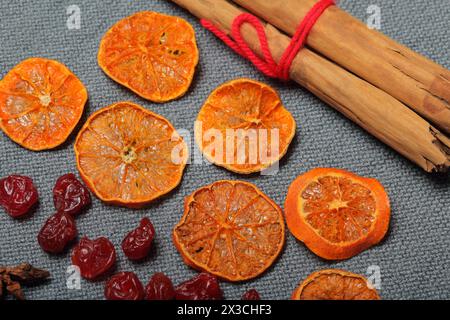 Dried tangerines, cut into pieces to decorate the dessert. Nearby are dry cherries, anise and cinnamon sticks tied with red thread. On a gray backgrou Stock Photo