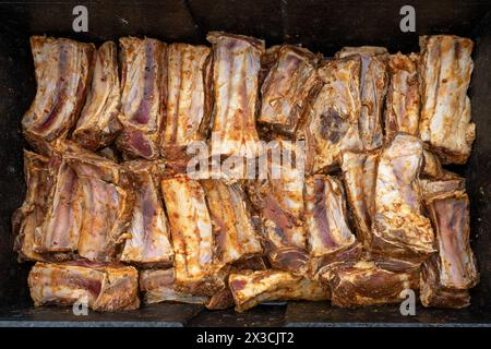 Seasoned and marinated beef short ribs are placed in a large black metal bowl, preparation for a barbecue party with many guests, top view from above, Stock Photo