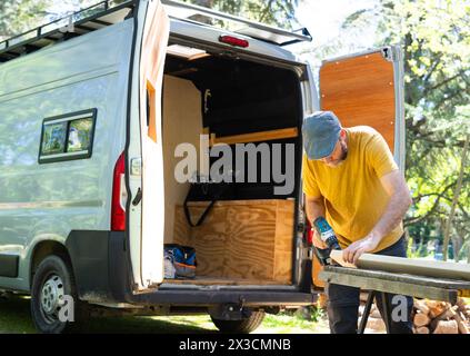 Caucasian man working to camperize his camper van outdoors Stock Photo