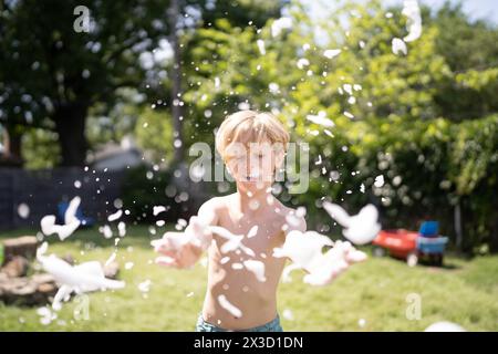 Boy playing with foam bubbles in backyard Stock Photo