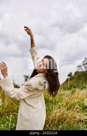 A beautiful young woman in white attire stands in a field, enjoying the summer breeze. Stock Photo