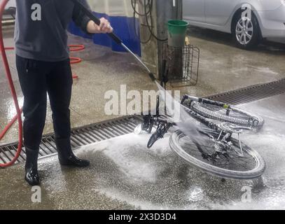 Woman washing bicycle with high pressure water spray Stock Photo