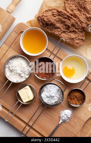 Gingerbread dough for Christmas and ingredients for making dough - egg, honey, spice, powdered sugar, butter, cacao, flour, baking soda on a wooden ba Stock Photo