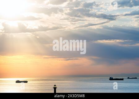 Ships in the roadstead against sun rays from the clouds Stock Photo